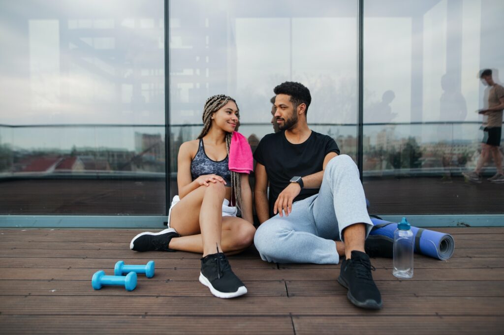 Couple in love resting after exercise outdoors on terrace, sport and healthy lifestyle concept.