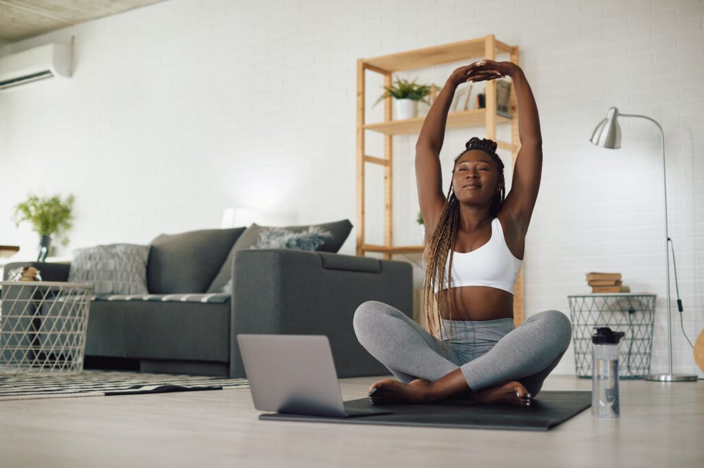 Young black athletic woman doing Yoga relaxation exercise during home workout.