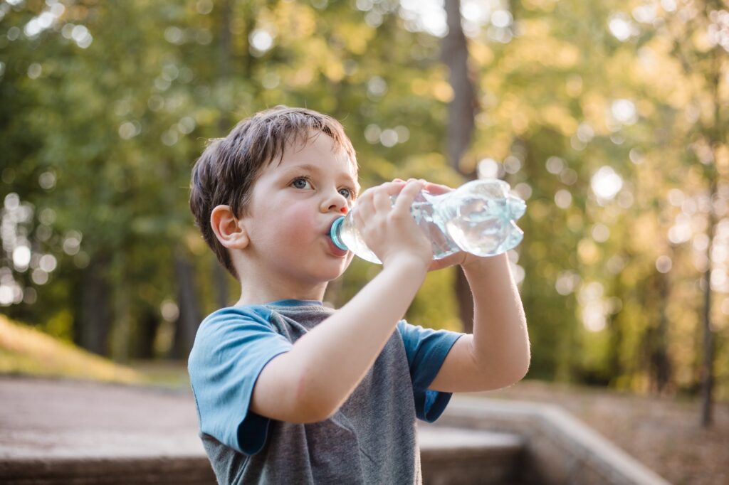 A boy drinks water on the street
