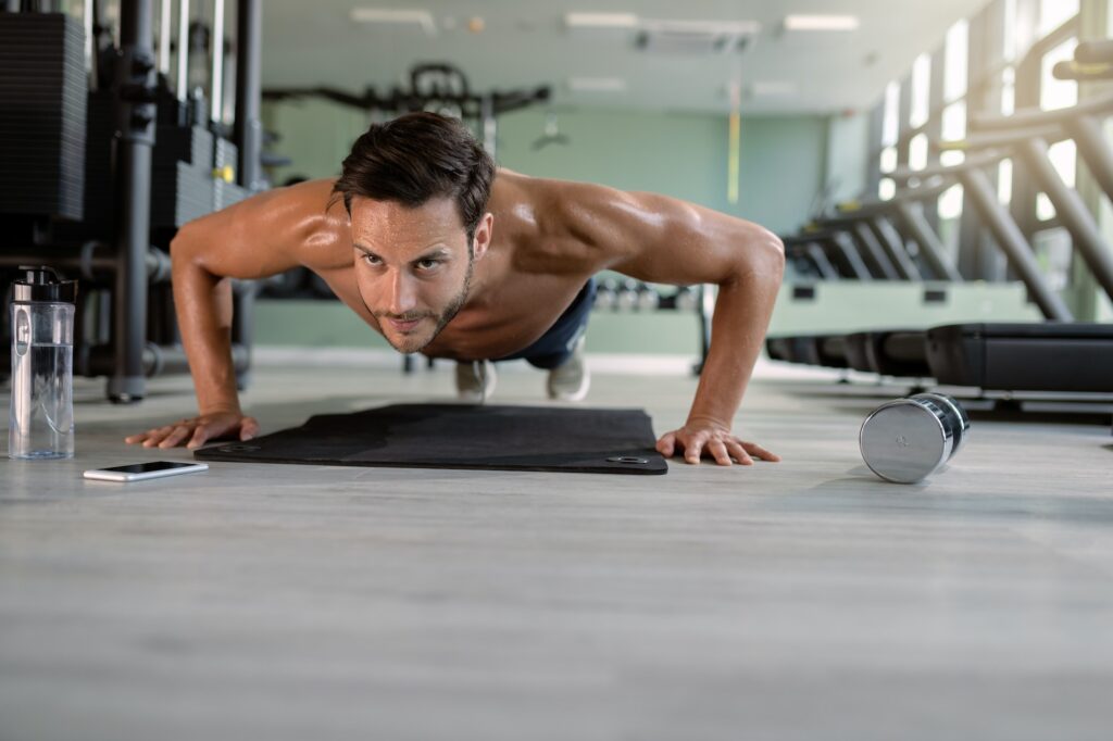 Exercise every day Muscular build man doing push-ups in a gym.